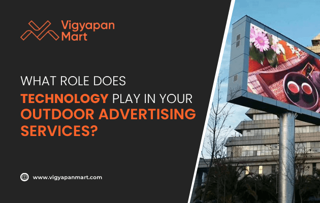 A digital billboard displays vibrant ads near a modern building. The text reads, “What role does technology play in your outdoor advertising services?” with the Vigyapan Mart logo and website at the bottom.