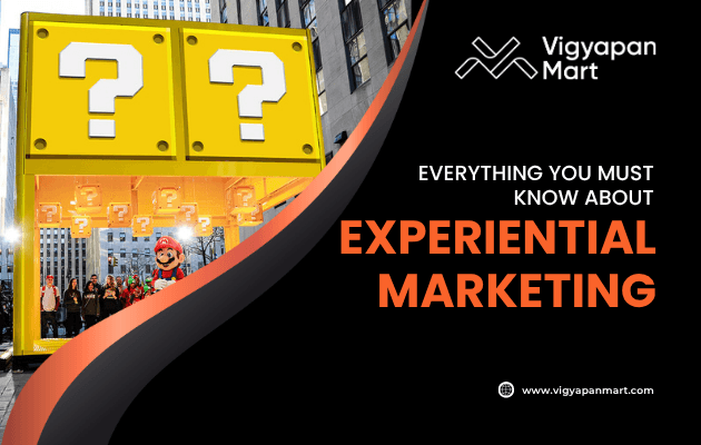 Promotional graphic for Vigyapan Mart featuring a large Super Mario-themed question block display in a city, with the text Everything you must know about Experiential Marketing.