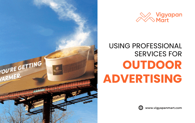 A large billboard advertising Panera Bread with a steaming soup, and text reading YOURE GETTING WARMER. Next to it, text says “Using professional services for outdoor advertising” and the Vigyapan Mart logo and website.