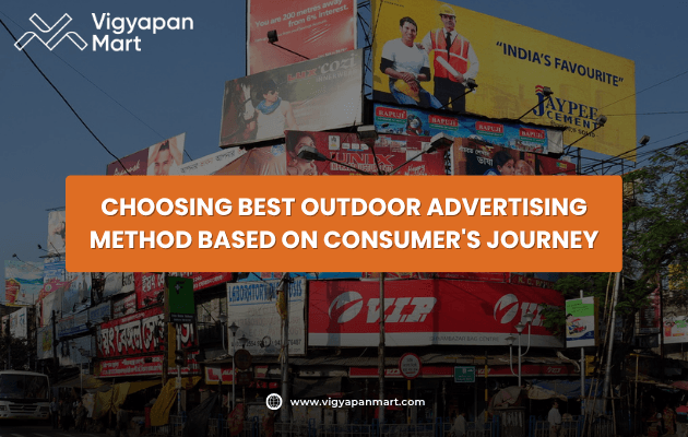 A busy street filled with colorful billboards and advertisements; an orange banner in the center reads, Choosing Best Outdoor Advertising Method Based on Consumers Journey. Vigyapan Mart logo and website appear above and below.