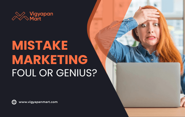 Woman sitting at a desk with a laptop, holding her forehead in shock or regret, featured alongside Vigyapan Mart graphic text “Mistake Marketing: Foul or Genius?” with logo and website link.