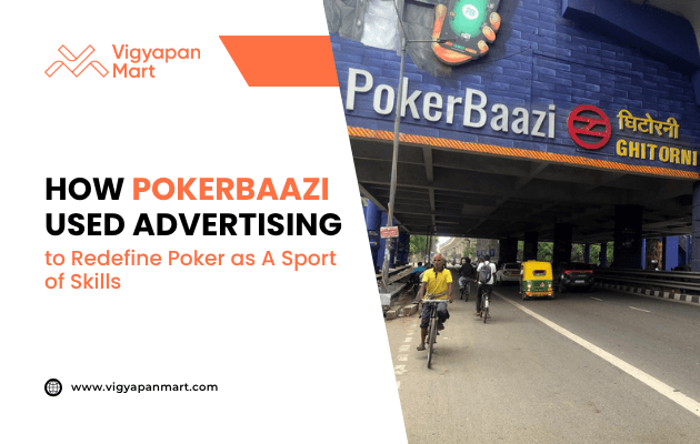Large outdoor advertisement for PokerBaazi displayed on a metro station wall above a busy street with cyclists, pedestrians, and vehicles. Overlay text reads “How PokerBaazi Used Advertising to Redefine Poker as a Sport of Skills” with Vigyapan Mart branding, emphasizing impactful brand positioning through outdoor advertising.