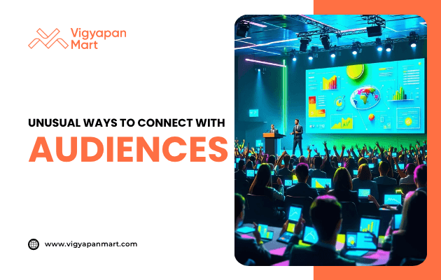 A speaker presenting on stage with a large colorful digital screen showing graphs and maps, while an engaged audience raises hands. Overlay text reads “Unusual Ways to Connect with Audiences” with Vigyapan Mart branding, emphasizing innovative audience engagement strategies.