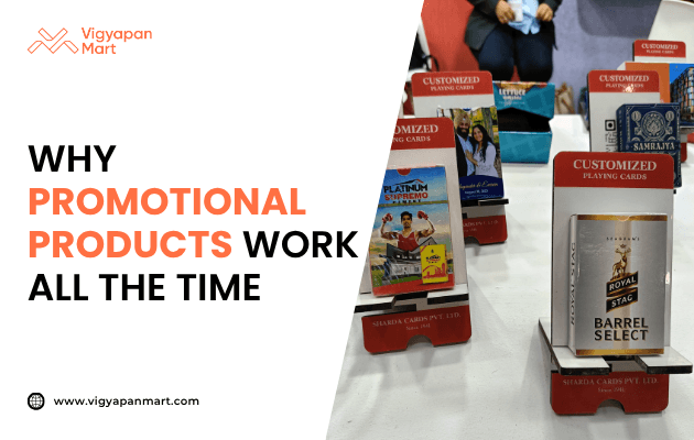 Vigyapan Mart graphic explaining why promotional products work all the time, featuring customized branded playing cards including Royal Stag Barrel Select and Sandela displayed on stands.