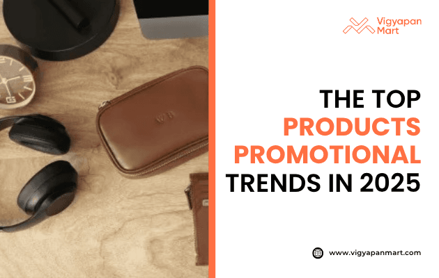 Vigyapan Mart graphic about the top promotional product trends in 2025, featuring stylish branded items including wireless headphones, a leather pouch, a modern clock, and premium lifestyle accessories placed on a wooden surface.
