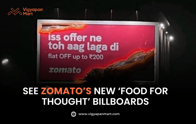 Vigyapan Mart graphic featuring a Zomato billboard with bold text in Hindi, “Iss offer ne toh aag laga di – flat OFF up to ₹200,” on a fiery red background. Below, the caption reads “See Zomato’s New ‘Food for Thought’ Billboards.” Vigyapan Mart logo and website are displayed.