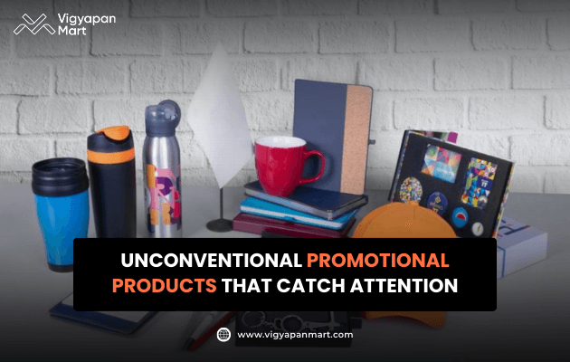 Vigyapan Mart creative showcasing a variety of unique promotional products like mugs, bottles, notebooks, tech accessories, and quirky items. Text overlay reads “Unconventional Promotional Products That Catch Attention.