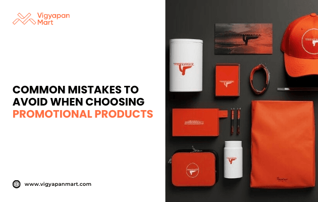 Flat lay of branded promotional products in red and white theme including cap, notebooks, drinkware, pouch, keychain, and stationery with logo imprint. Marketing banner text reads 'Common Mistakes to Avoid When Choosing Promotional Products' by Vigyapan Mart, focusing on effective merchandise selection.