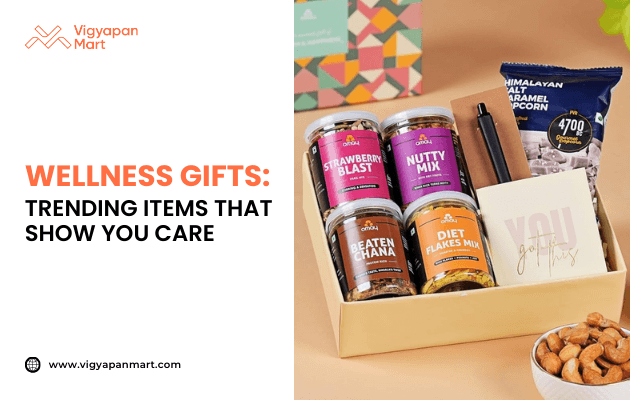 Gift box of wellness products containing jars labeled Strawberry Blast, Nutty Mix, Beaten Chana, and Diet Flakes Mix, presented with colorful packaging. Marketing banner text reads 'Wellness Gifts: Trending Items That Show You Care' by Vigyapan Mart, highlighting health-focused corporate gifting ideas.