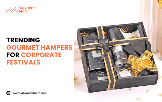 Luxury black gift hamper box with golden ribbon containing premium gourmet items and branded products, alongside text 'Trending Gourmet Hampers for Corporate Festivals' by Vigyapan Mart, emphasizing luxury corporate gifts, festive hampers, and premium business gifting trends.