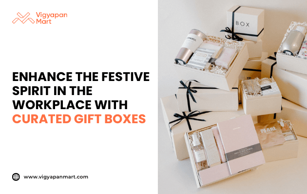 Stack of curated festive gift boxes filled with wellness and lifestyle items, wrapped in white packaging with black ribbons, alongside text: Enhance the festive spirit in the workplace with curated gift boxes. Vigyapan Mart branding and website shown.