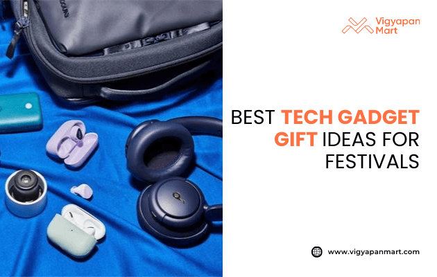 Assorted tech gadgets including wireless earbuds, headphones, smart camera, and portable devices placed on a blue fabric beside a backpack, with text: Best tech gadget gift ideas for festivals. Vigyapan Mart branding and website shown.