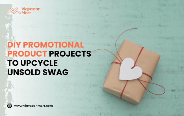 Brown paper gift wrapped with red string and white heart tag on a teal background, next to text “DIY Promotional Product Projects to Upcycle Unsold Swag,” with Vigyapan Mart logo and website.