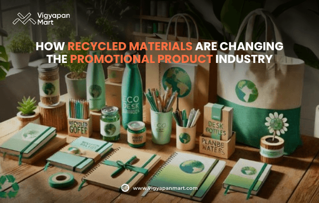 Eco-friendly promotional products made from recycled materials, including notebooks, pens, bottles, bags, and cups with Earth and green designs. Text: "How recycled materials are changing the promotional product industry" by Vigyapan Mart.