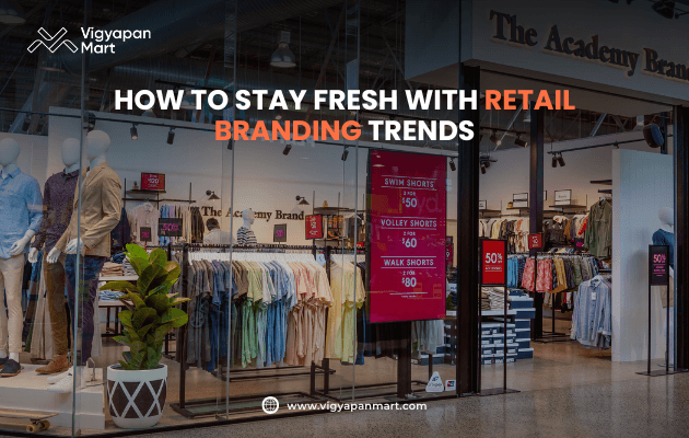 Modern retail clothing store entrance with mannequins in casual outfits, racks of colorful shirts, and bold red sale signage promoting 50% discounts; overlay text reads "How to Stay Fresh with Retail Branding Trends" by Vigyapan Mart.