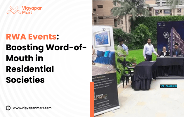Promotional event at a residential society with two men and a woman at a table. Display banners showcase real estate offerings. Keywords: RWA events, word-of-mouth, residential.