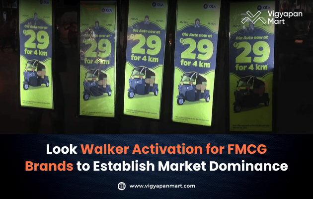 Four illuminated billboards display a promotion for Ola Auto with a price of 29 for 4 km. A banner below highlights "Look Walker Activation for FMCG Brands" from Vigyapan Mart.