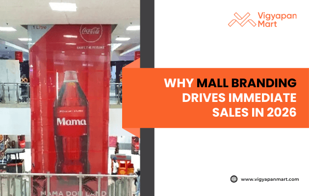 A large Coca-Cola display bottle labeled "Mama" in a shopping mall atrium. Overlay text reads: "Why Mall Branding Drives Immediate Sales in 2026." Vigyapan Mart logo in top right.