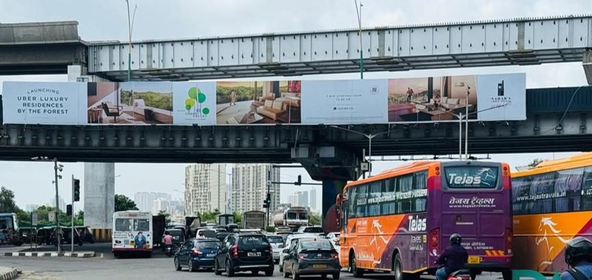 Outdoor advertising in India showing billboard and bus ads in a city street.